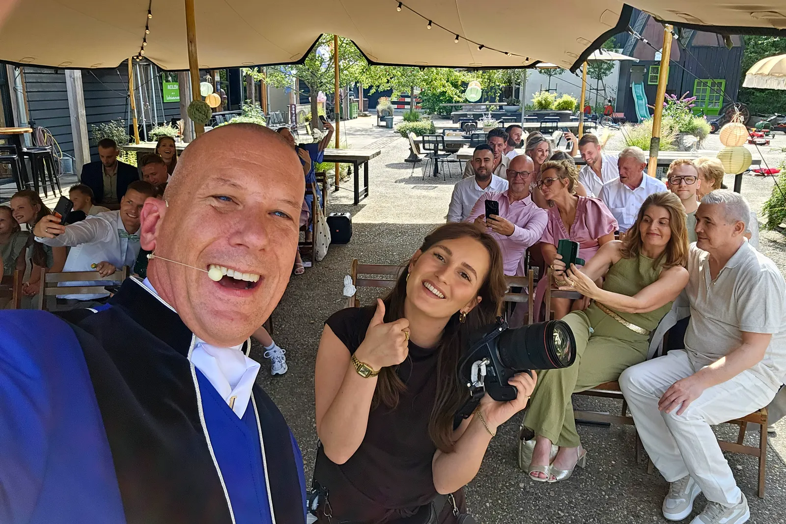 Ceremonieel trouwen — Jasper maakt lachend een selfie met gasten op een buitenlocatie