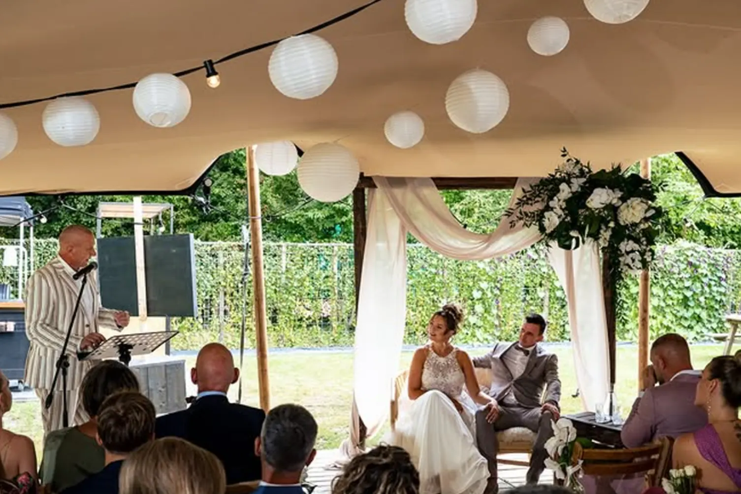 Gasten onder sfeervolle lichtjes tijdens de ceremonie