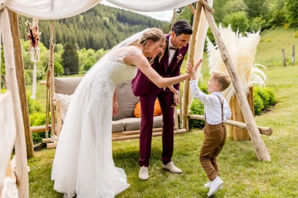 Bruidspaar geeft een kind een high five tijdens de trouwceremonie